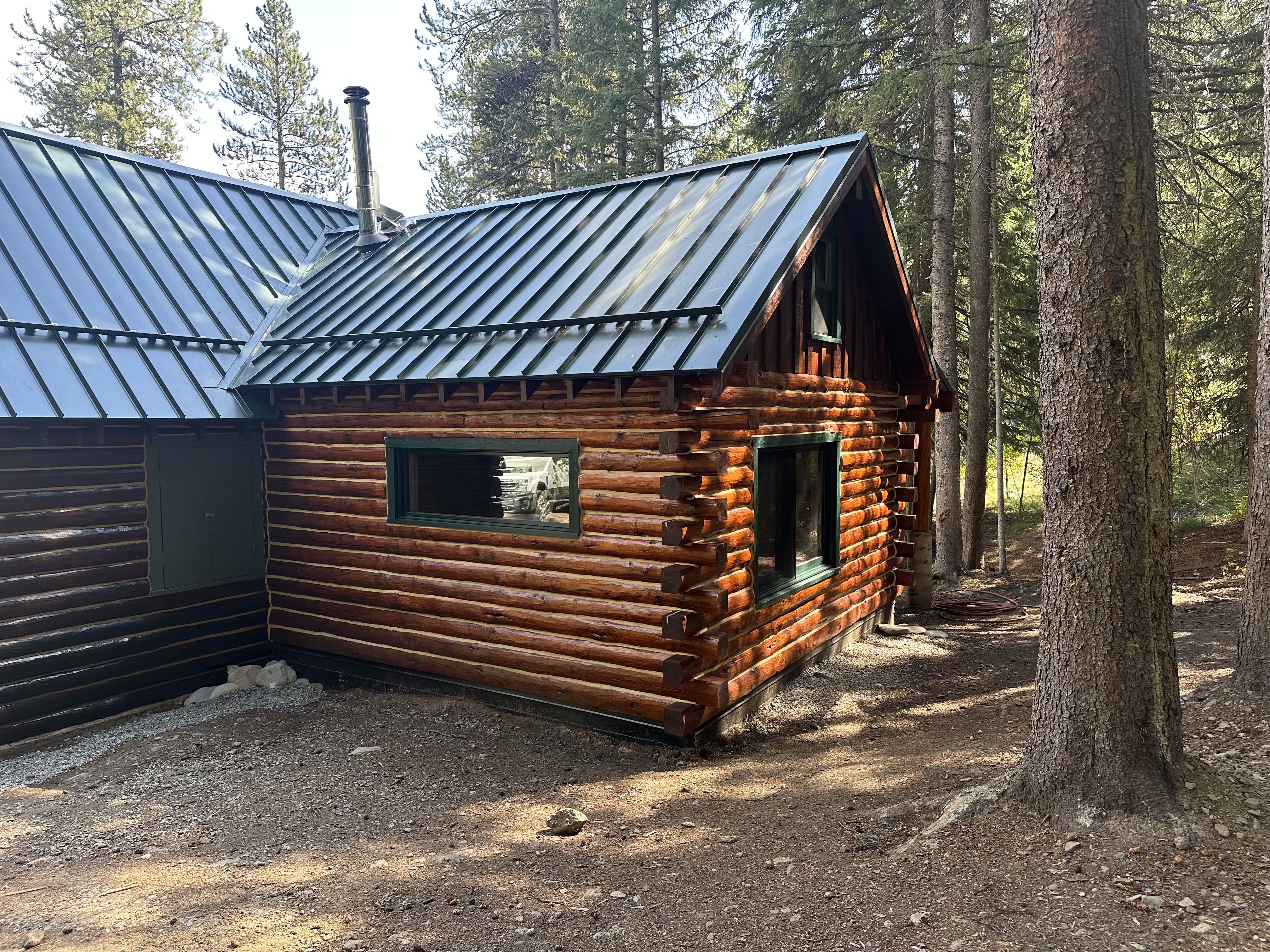 Restored log home with new standing-seam metal roof in the Idaho pines